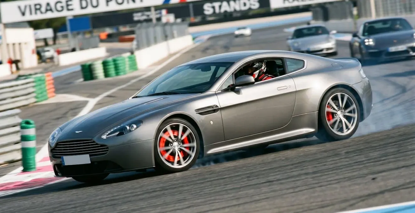 Aston Martin V8 Vantage en action lors d'une session track day sur circuit français, démontrant l'usage intensif nécessitant un entretien adapté